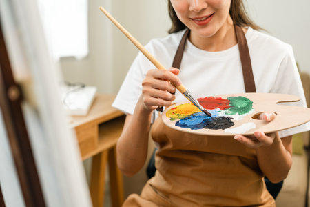 Asian woman artist working on painting with brush and variant acrylic color. Female artist painter on canvas in creative studio as art conceptの写真素材