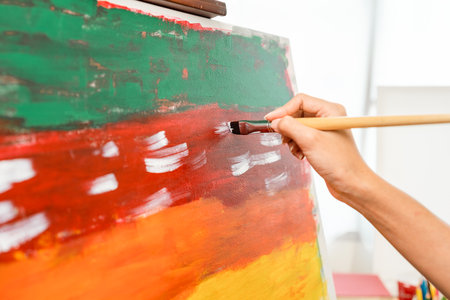 Close up hand Asian woman artist working on painting with brush and variant acrylic color. Female artist painter on canvas in creative studio as art conceptの写真素材