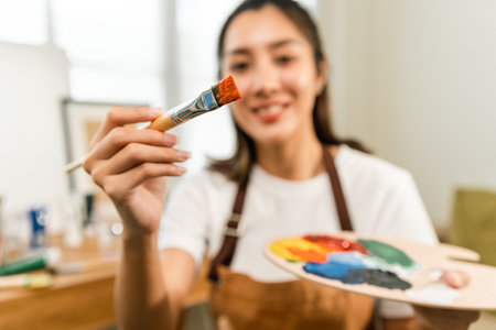 Asian woman artist working on painting with brush and variant acrylic color. Female artist painter on canvas in creative studio as art conceptの写真素材