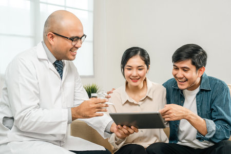 Asian family discussing fertility with a pediatrician. Young couple patients in fertility clinic consulting about IVF or IUI with doctor. Couple relationship therapy with a counselorの写真素材