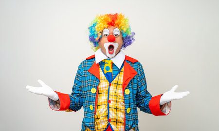 Mr Clown. Portrait of Funny shocked face comedian Clown man in colorful costume wearing wig standing posing smiling to camera. Happy expression amazed bozo in various pose on isolated background.の写真素材