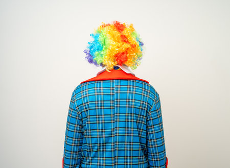 Rear view Mr Clown. Back behind Portrait of Funny comedian face Clown man in colorful uniform wearing wig standing. Happy expression male bozo in various pose on isolated background.の写真素材