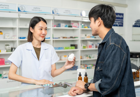 Pharmacist recommends medicines to customers.Taking the questions of medication. Asian female pharmacist giving prescription medications to customers at drugstore shelves.の写真素材