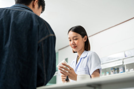 Pharmacist recommends medicines to customers.Taking the questions of medication. Asian female pharmacist giving prescription medications to customers at drugstore shelves.の写真素材