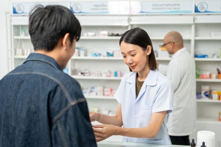 Pharmacist recommends medicines to customers.Taking the questions of medication. Asian female pharmacist giving prescription medications to customers at drugstore shelves.の写真素材