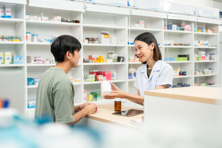 Pharmacist recommends medicines to customers.Taking the questions of medication. Asian female pharmacist giving prescription medications to customers at drugstore shelves.の写真素材
