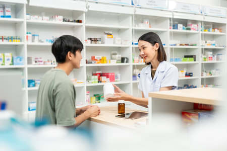 Pharmacist recommends medicines to customers.Taking the questions of medication. Asian female pharmacist giving prescription medications to customers at drugstore shelves.の写真素材