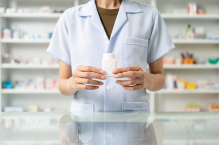 Close up woman hands holding medicine bottle near drug shelves. Pharmacist checks inventory of medicine in pharmacy drugstore. Professional Female Pharmacist wearing uniformの写真素材