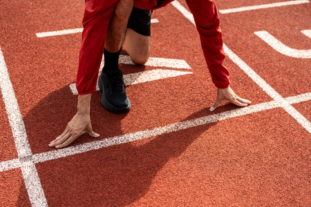 Young handsome indian man doing start pose before running exercise on track in sport stadium. Challenge race of athletes running in the starting point. Young asian man in sport athlete uniformの写真素材