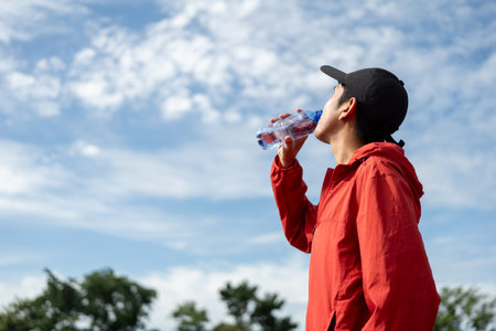 Handsome indian man drinking water after workout exercising in the stadium. Young asian man drinking water after jogging running outdoor at running track. Healthy and active lifestyle concept.の写真素材