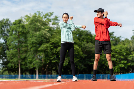 Couple asian jogging and running outdoors at sport stadium warming up stretching before workout. Happy healthy Man woman wearing sportswear jogging. Workout exercise Healthy and lifestyle.の写真素材