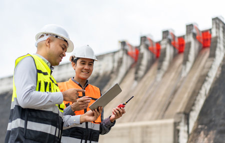Confident asian two maintenance engineers man inspection discussstion with tablet at construction...