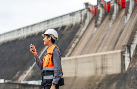 Professional asian maintenance engineer man with safety helmet in construction site dam with hydroelectric power plant and irrigation. Manager engineer man working at project big building.の写真素材