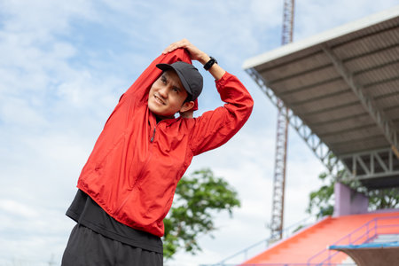 Young asian man wearing sportswear running outdoor. Portraits of Indian man stretching arm before running at sport stadium. Training athlete work out at outdoor concept.の写真素材