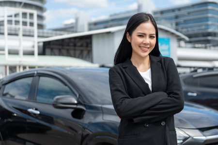 Young beautiful asian business woman buying new car. she was standing in near car on the roadside downtown city background. Smiling business female driving vehicle on the road on a bright dayの写真素材