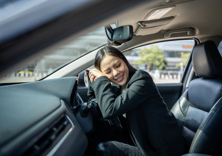 Young beautiful asian business women getting new car. Happy smiling female driving vehicle on the road hugging steering wheel touching detail car interior. Business woman buying driving new carの写真素材