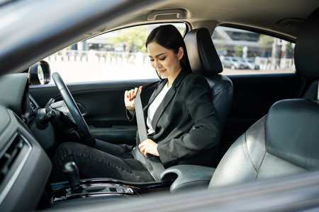 Young beautiful asian business women getting new car put on safety belt. she very happy and excited sit and put on seatbelt. Smiling female buying new car safety driving vehicle on the roadの写真素材