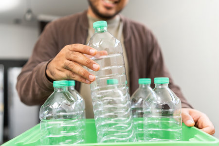 A young man arranged plastic bottles into a box. He assumes plastic bottles will sort of trash before throwing them into the bin. World environment day. Recycle waste reduce environmentally friendlyの写真素材