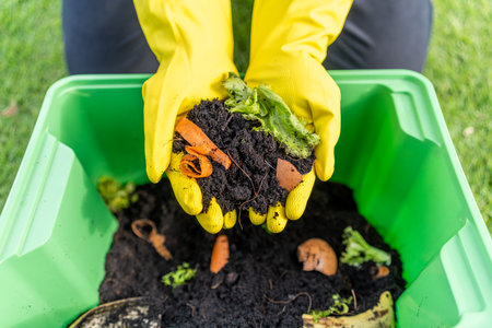 Ecology compost supply Kitchen waste recycling composter environmentally friendly. The young man throws leftover fruit peel egg shell and vegetables reduce wasteの写真素材