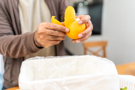 Ecology compost supply Kitchen waste recycling composter environmentally friendly. The young man throws leftover fruit peel and vegetables reduce wasteの写真素材