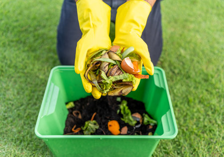 Ecology compost supply Kitchen waste recycling composter environmentally friendly. The young man throws leftover fruit peel egg shell and vegetables reduce wasteの写真素材