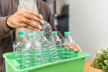 A young man arranged plastic bottles into a box. He assumes plastic bottles will sort of trash...