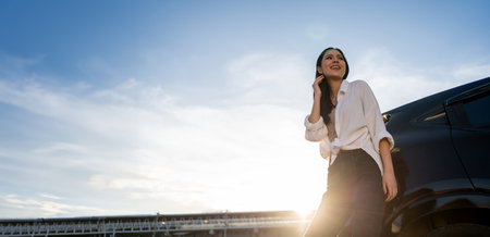 Young beautiful asian women buying new car. she was standing near car on the roadside. Beautiful moment blue sky Smiling female driving travel by vehicle on the road on a bright day with sun light.の写真素材