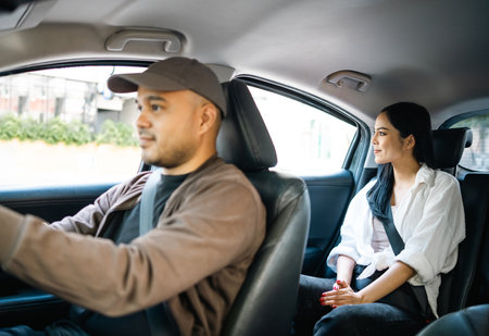 Young asian woman traveling in the downtown city with taxi driver service. Female passenger sitting in backseat calling taxi driver by application.の写真素材