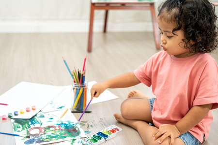 Happy moment little cute girl creating and water color painting activity with paint brushes on frame canvas at living room. Kids activity. Child physical, Emotional, Cognitive development concept.の写真素材