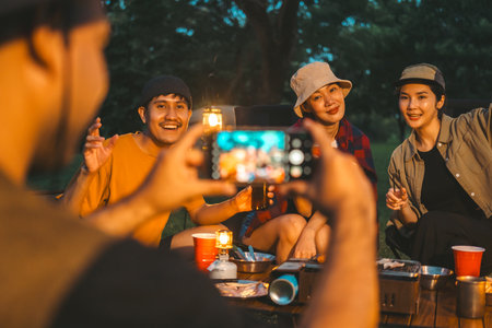 Group of asian people friend party camping in nature making toasting and taking photo by smartphone to share on social media. Hangout party outdoor in campsite nature on holiday weekend vacationの写真素材