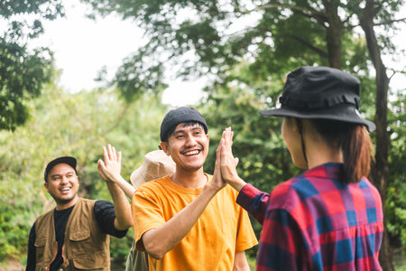 Group of young traveller people giving high five for friendship while camping in nature trip. Happy asian people group friend travel together. Enjoying camping on weekend vacation time.の写真素材