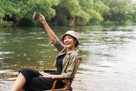 Young asian woman traveller drinking coffee in nature forest background. Happy Beautiful woman living middle of a lot of tree. Breathing the fresh air on her vacation weekend holiday trip.の写真素材