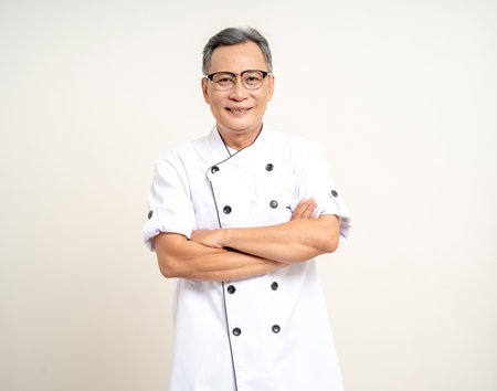 Handsome senior chef asian mature old man standing arm crossed on isolated white background. Happy Portrait of cheerful smiling senior asian man. Mature People and lifestyleの写真素材