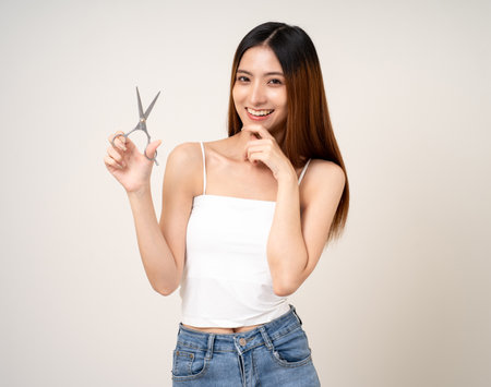 A beautiful woman with long hair is thinking about what style she should cut her hair with scissors or going to a beauty salon.の写真素材