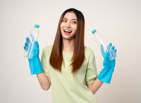 Young asian beautiful woman holding plastic of bottle assume Garbage sorting before throwing them into the bin. Activist environmental woman in green shirt with recycle and sustainability concept.の写真素材