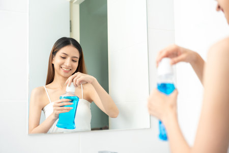 Young asian woman with mouthwash for the health of teeth in restroom. Take care and good dental health fresh breath with mouthwash.の写真素材