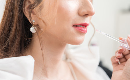 Beautiful young asian bride with wedding makeup and hairstyle before ceremony. Preparation for wedding applying with cosmetic by artist makeup.の写真素材