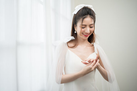 Beautiful asian bride with fashion wedding hairstyle and makeup. Portrait of young gorgeous bride wedding studio shot in white room.の写真素材