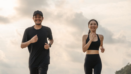 Asian Couple jogging and running outdoors sea sand beach. Sporty people wearing sportswear jogging. Male female athlete running during sunset on the beach. Workout exercise. Healthy and lifestyle.の写真素材