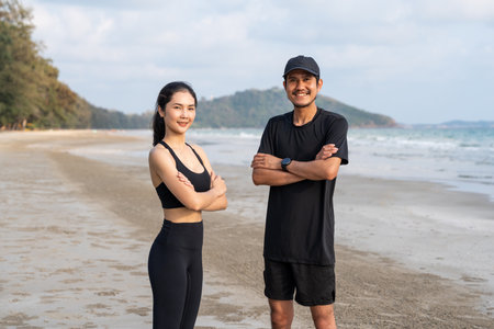 Asian Couple stretching arms and legs before running outdoors sea sand beach. Sporty people warm up body before jogging. Athlete running during sunset on the beach. Workout exercise.の写真素材