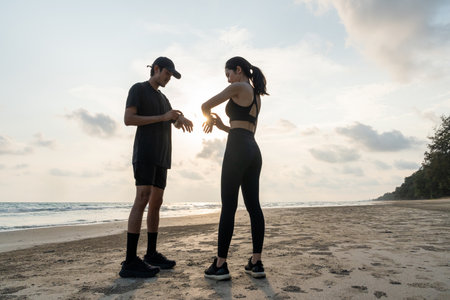 Asian Couple stretching arms and legs before running outdoors sea sand beach. Sporty people warm up body before jogging. Athlete running during sunset on the beach. Workout exercise.の写真素材