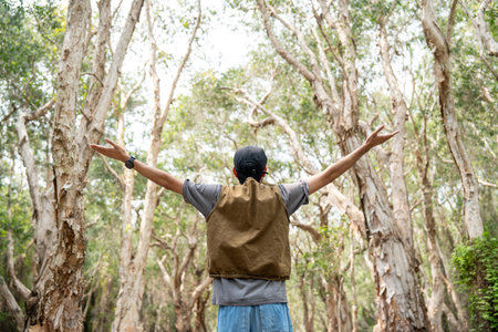 Young asian man traveling alone in the forest. Happy weekend on vacation time. Attractive male traveler walking in nature spend time enjoy with holidayの写真素材