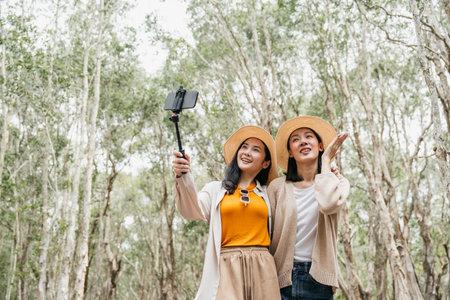 Happy asian friends traveling in the forest. Happy weekend on vacation time. Attractive Lesbian couple female traveler walking in nature spend time enjoy with holidayの写真素材