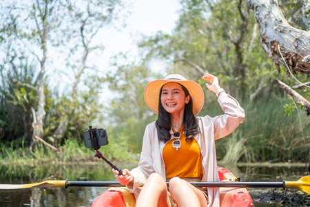 Holiday travel activities. Happy asian woman rowing a canoe or kayak in mangrove forests. Young traveler with kayak at botanical garden tropical mangrove forest in a national park.の写真素材