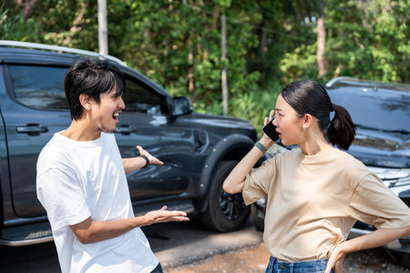 Asian man and woman drivers arguing after traffic collision accident feeling serious and stressed. Parked on side way road Call Emergency assistance or insurance claim service. Car Crashの写真素材