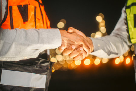 Two Asian engineer man with safety helmet standing front of oil refinery. Industry zone gas petrochemical. Factory oil storage tank and pipeline. Workers work in the refinery construction buildingの写真素材