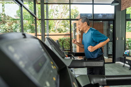 Senior old man runner exercise indoor gym. fitness man jogging wearing sportswear. Mature athlete man in sportswear Workout running on the treadmill.の写真素材