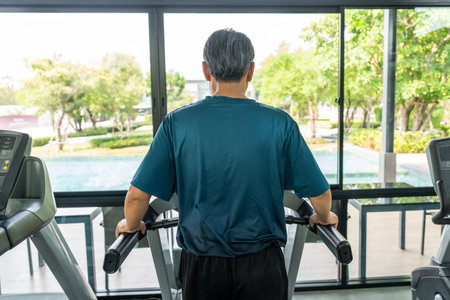 Senior old man runner exercise indoor gym. fitness man jogging wearing sportswear. Mature athlete man in sportswear Workout running on the treadmill.の写真素材