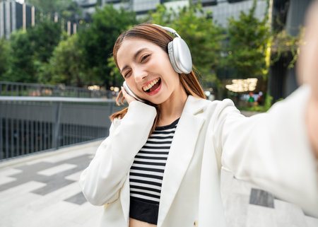 Young asian woman fashion lifestyle with headphone standing posing dancing in urban city downtown. Happy attractive charming asian female listen to the music and dance. People and lifestyle.の写真素材