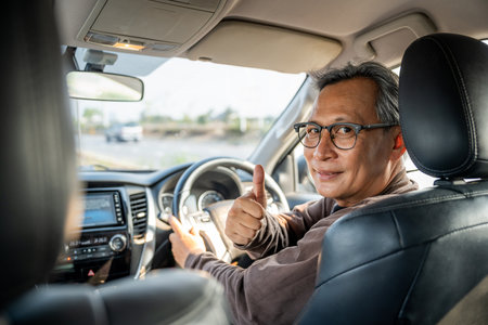 Senior Asian man drives a car vehicle on a clear day. With beautiful blue sky. He smiling driving to travel by car. Old man getting new car.の写真素材